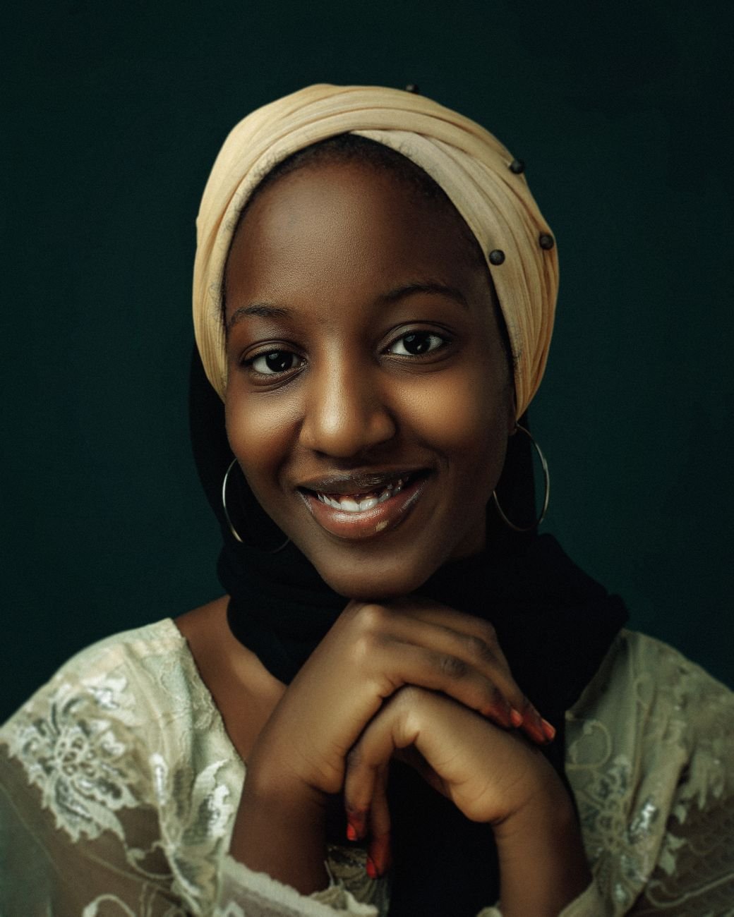 Portrait of a young woman wearing a traditional headscarf, smiling warmly.
