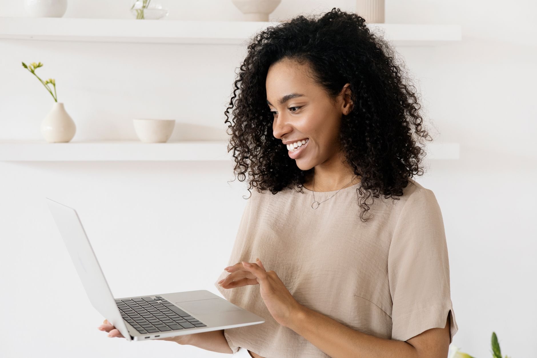 Smiling woman working on a laptop in a modern home office, highlighting freelance lifestyle.